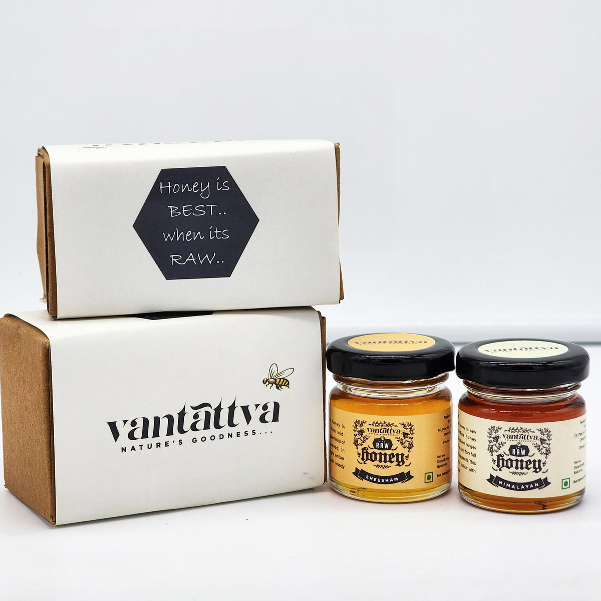 Two jars of honey on a display of 'Vantattva' boxes.